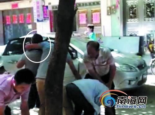 据梁居法老人的儿子指认,图中便衣民警抓获的2名涉赌人员,其中一人是梁居法老人(白圈中被人扼住脖子的人)