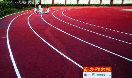 10月27日下午,几名学生在铁军小学玩耍,身后是新铺设的塑胶地面。南都记者 张明术 摄
