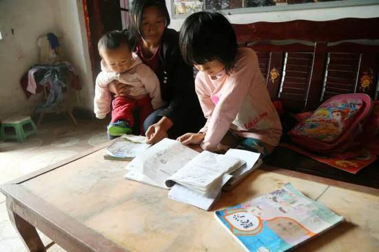 劉麗英坐在孩子身邊照顧做功課