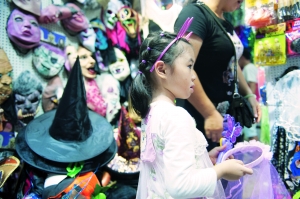 一名小女孩正在一德路的店铺里挑选幼儿园万圣节活动需要的服饰。