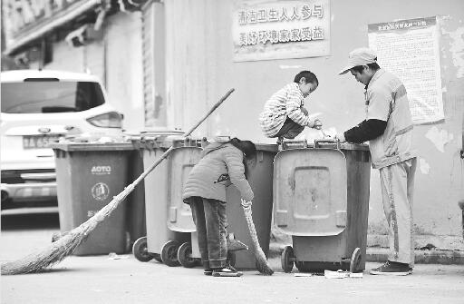 阳阳在垃圾桶上帮父亲捡拾垃圾 记者高歌 摄