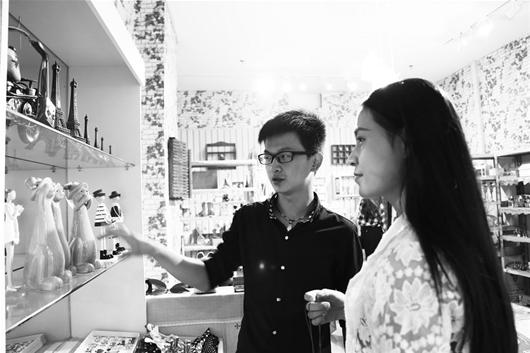 柯焱（左）正在向顾客介绍店里的手工品 （记者宋锐 通讯员郑佳佳摄）