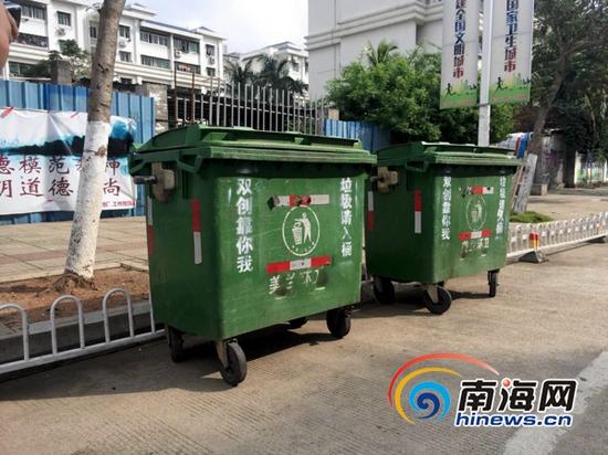 美兰区美祥路上,两个绿色的大垃圾收集桶放置在路边,把划好的车道占去了一半。(南海网记者周静泊摄)