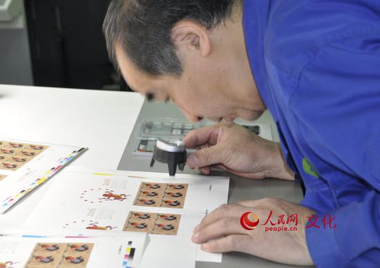 印刷車間里的工作人員正在用放大鏡檢查印刷效果。(人民網(wǎng) 王鶴瑾 攝)