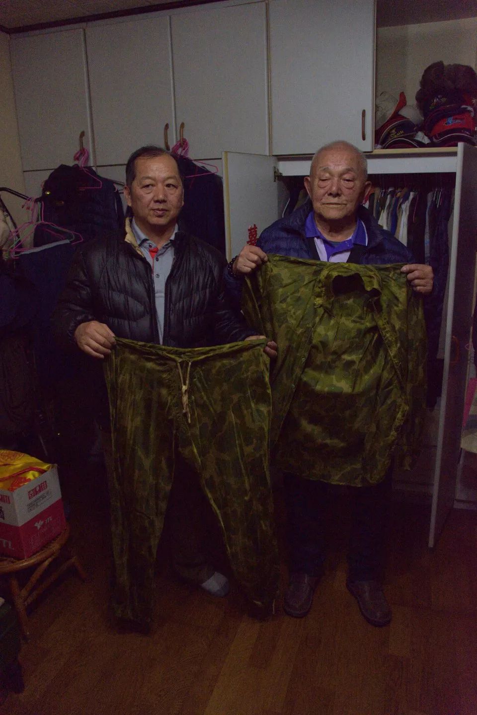 李云棠（右）展示当年女村民为他用降落伞做的衣服。