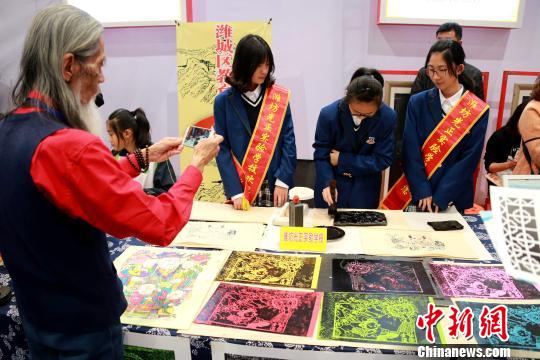 图为小学生在第3届中国(潍坊)民间艺术博览会上体验木板年画制作。 梁犇 摄