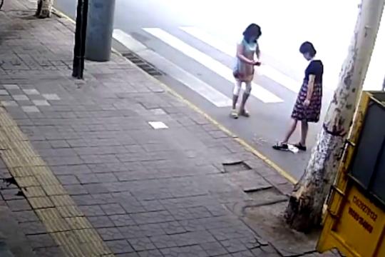 图为两女子倒烟头拍照。视频截图