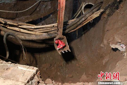 消防员通过挖掘机斗进入坑底对管道进行捆扎,以减少其对救援的影响。 钟欣 摄