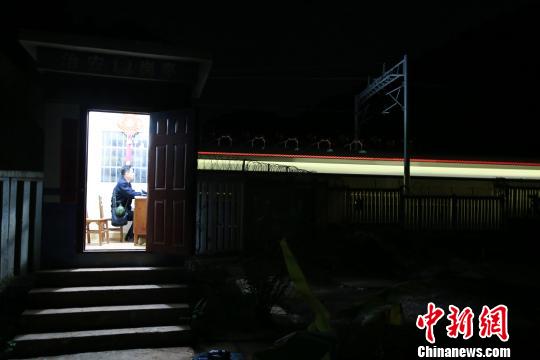 夜里的南钦17号治安岗亭显得孤寂,一列动车呼啸而过。 黄军华 摄