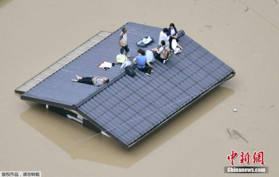 当地时间2018年7月7日,日本,日本自5日以来持续大范围普降暴雨,截至6日傍晚,大雨已经造成3人死亡、9人失踪,新干线部分路段停运。日本近日受到本州附近滞留锋面的影响,大气状态不稳定,多地普降暴雨,气象厅6日下午对福冈县、佐贺县和长崎县发出最高级别警报。图为民众爬上屋顶等待救援。 日本连日暴雨已致至少51人死亡 逾356万人需疏散