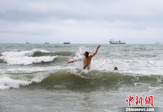 游客在三亚海边嬉水。 王晓斌 摄 台风“山神”横穿海南 游客不惧风雨三亚海边嬉水