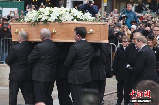 资料图：当地时间3月31日，英国著名物理学家霍金的葬礼在剑桥圣玛丽教堂举行。大约500名霍金的亲友和同事受邀出席了这场私人丧礼，但仍有各界人士在教堂外为霍金送行。图为金黄色的、躺着霍金遗体的棺椁，被6位其生前友人肩扛着缓缓抬进教堂。 中新社记者 张平 摄