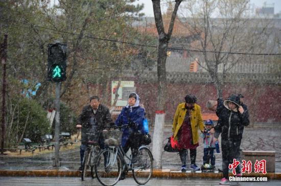 4月3日,民众在雪中步行过马路。当日,呼和浩特迎来降雪,气温骤然下降,不少民众纷纷加衣保暖。<a target='_blank' href='http://www.chinanews.com/'>中新社</a>记者 刘文华 摄 入春的北京发布暴雪蓝色预警