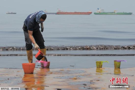 警察在Banua Patra海滩清理浮油。