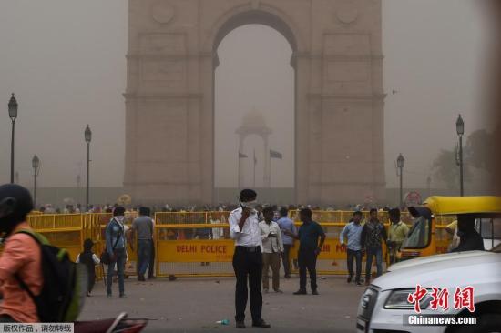 当地时间5月2日，印度新德里的一名交警（中）在沙尘暴天气中带着面巾指挥交通。