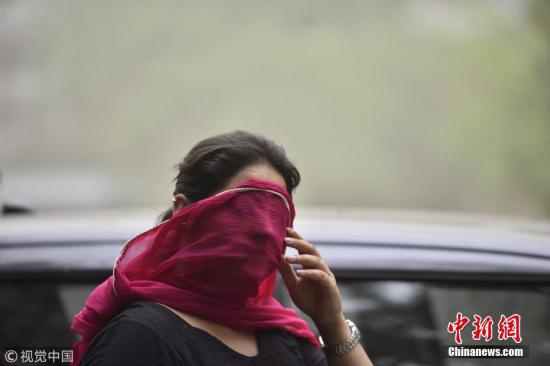 图为当地时间5月2日，印度新德里的一名女子用纱巾遮住脸，躲避沙尘天气的侵扰。 图片来源：视觉中国