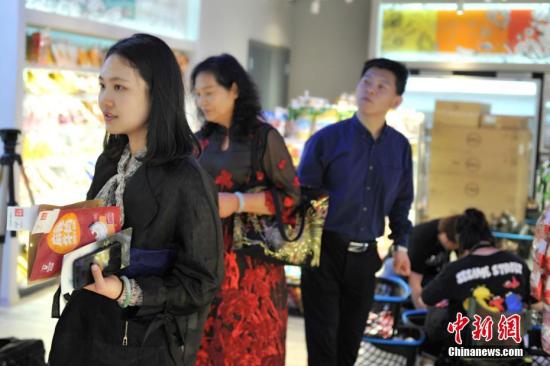 资料图：记者探访“无人超市”，感受“刷脸”购物。图为顾客购物后排队结算。 中新社记者 韩冰 摄