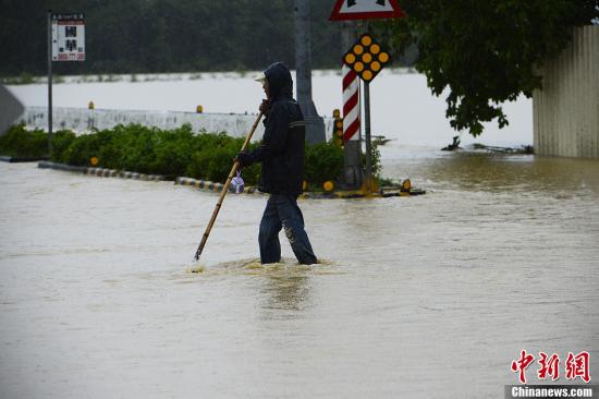 资料图：台湾民众在被雨淹没的马路出行。刘震 摄