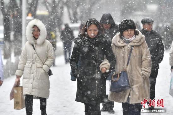 2月1日,新疆烏魯木齊市迎來降雪天氣。圖爲民衆在紛紛揚揚的雪中出行。<a target='_blank' href='http://www.chinanews.com/'>中新社</a>記者 劉新 攝