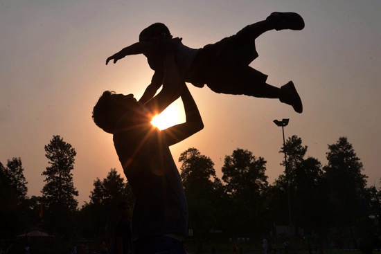 父亲节，印度一位父亲带着孩子在公园里玩耍。
