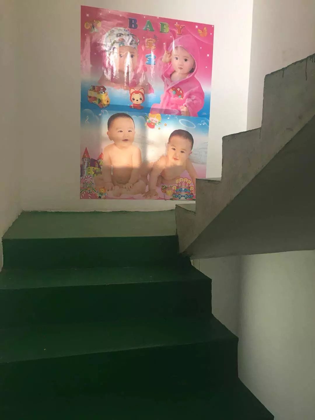 （新房楼梯口的墙面上，张福如为儿子贴上几张娃娃画像，寓意早生贵子。）