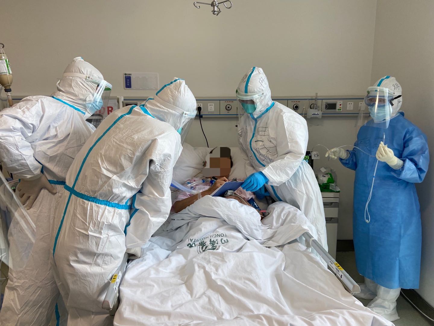 同济医院中法新城院区重症医学科主治医师冉晓和同事查房。其中一名患者将自己早上出现的身体情况写在纸上,告诉医护。