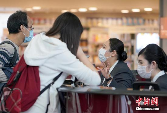 资料图：香港国际机场的工作人员戴口罩接受旅客问询。中新社记者 张炜 摄