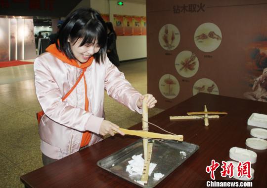 参观者现场体验“钻木取火”。 徐巧明 摄