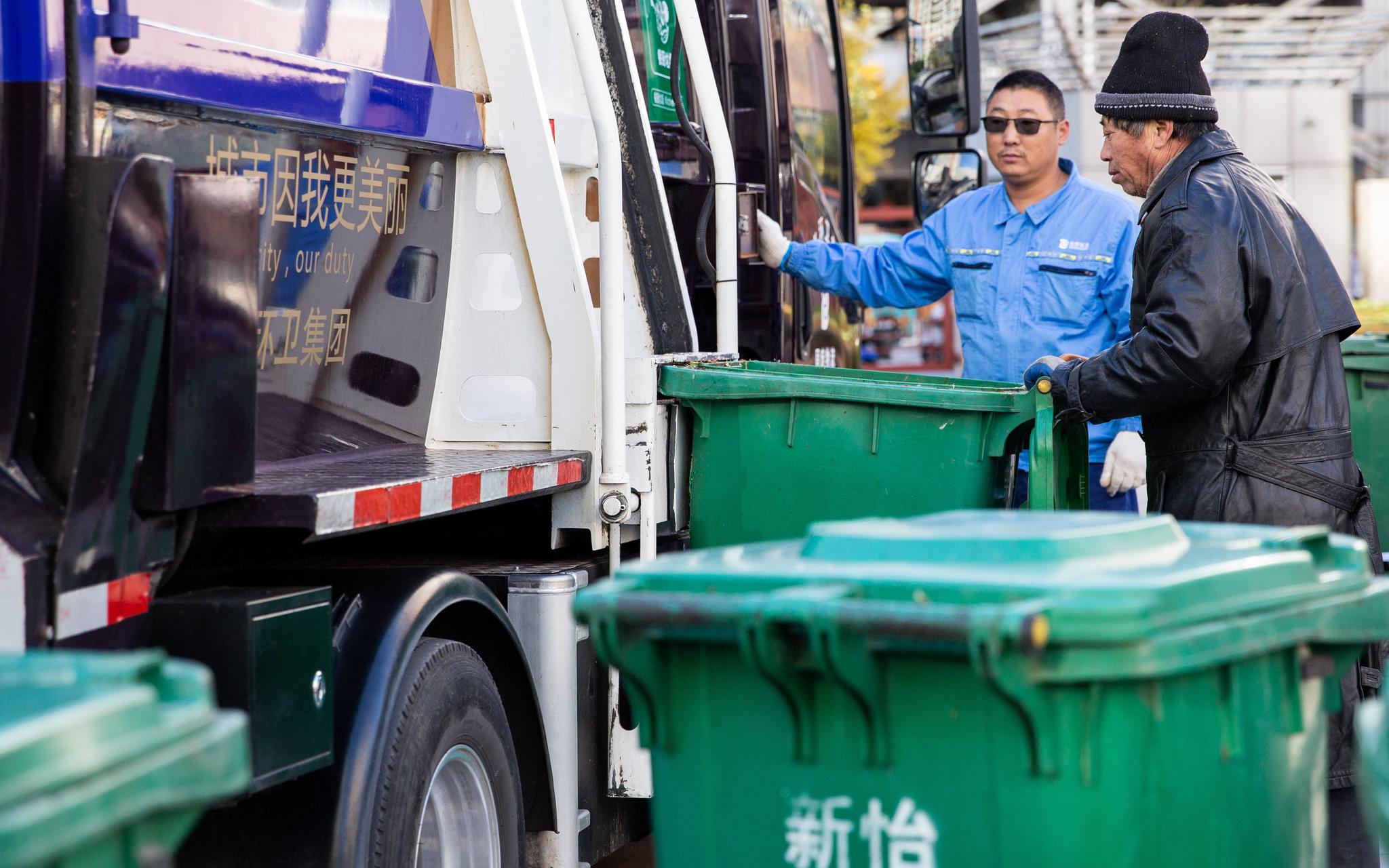 11月25日，崇外街道新怡家园，环卫集团工作人员正把小区厨余垃圾桶内的垃圾倒入运输车。新京报记者 李凯祥 摄