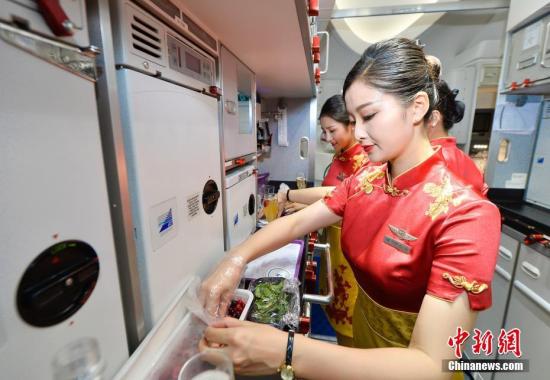 资料图:空姐在机舱里准备餐食。王东明 摄