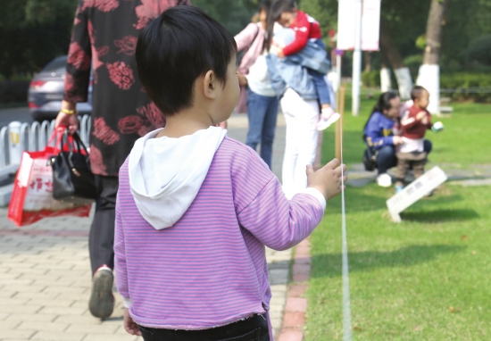 11月5日，长沙橘子洲景区，小朋友正试图去摸草坪边用于防护隔离的细绳。图/实习记者张云峰