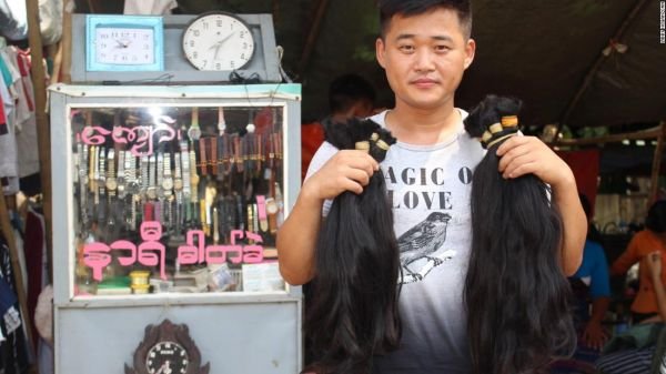 一位头发买家手里拿着他从仰光永盛市场买来的两束头发。