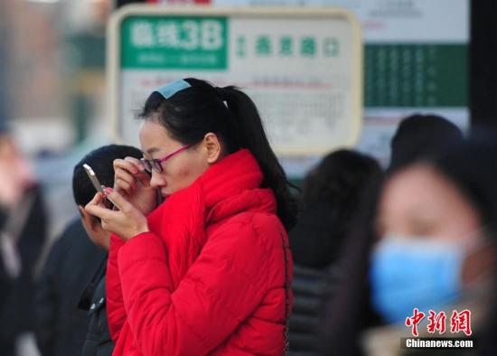 资料图:等待公交的女市民化妆,整理面容。 翟羽佳 摄
