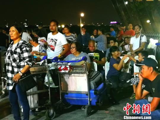 候机厅外不少滞留旅客将行李放在手推车上,靠着休息。 关向东 摄