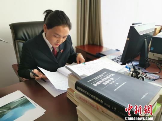 图为近日,白玛康卓整理一起公益诉讼的案卷材料。 张伟 摄