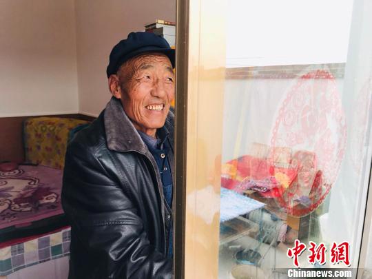 67岁的村民金富贵擦拭着新房子的玻璃。 艾庆龙 摄