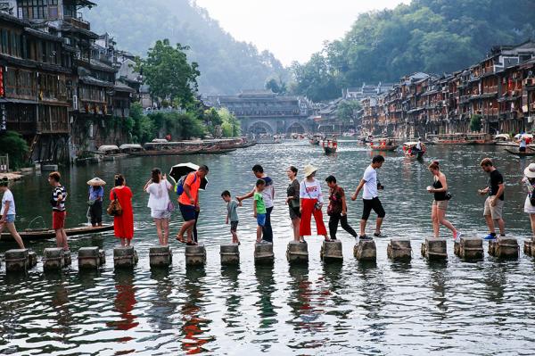 2017年8月5日，游客在湖南凤凰古城沱江上参观游览。视觉中国 资料图