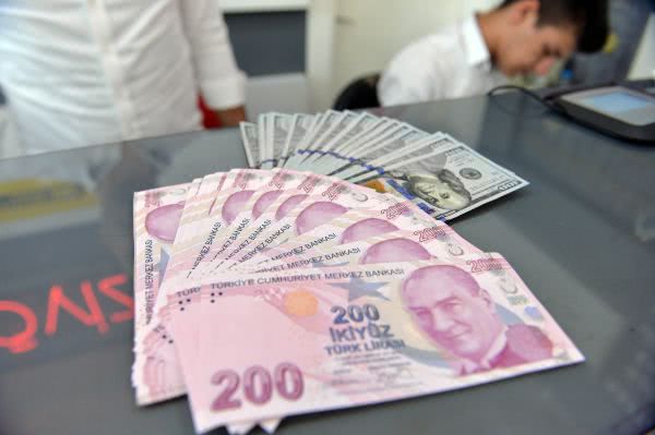 资料图片：8月10日，在土耳其安卡拉，一名男子展示土耳其里拉和美元纸币。 新华社发（穆斯塔法·卡亚摄）