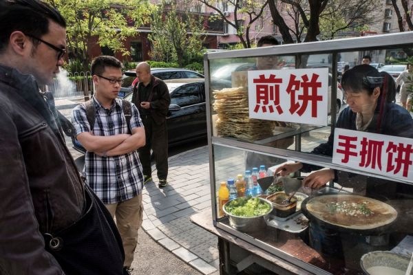 北京一个卖煎饼的摊贩。（美国《纽约时报》网站）