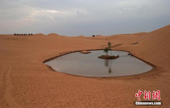 资料图：腾格里沙漠深处，一处洼地有一处神奇的小湖泊，被开发成旅游景点，不过，由于地下水开采加剧，这个湖泊越来越萎缩。陈杰 摄 图片来源：CFP视觉中国