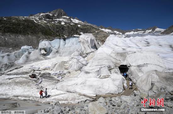 资料图：2015年7月14日，在瑞士阿尔卑斯山脉的罗纳冰川，一名女子在保护冰川的隔热材料附近进行冰上攀岩。瑞士罗纳冰川位于瑞士瓦莱州。瑞士壮美的冰川景观吸引着世界各地游客。受全球气候变暖影响，瑞士冰川不断消融。