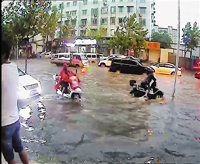 8月30日17时50分许，骑电动摩托车的张建伟（图右）跌倒在水中，他身旁的白色轿车打着双闪，却一直未出来人救援。视频截图