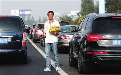 昨日，京藏高速进京方向康庄到八达岭路段拥堵，小贩在车辆中穿梭卖东西。新京报记者 王贵彬 摄
