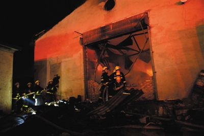 昨日凌晨，消防人员在发生爆燃的仓库外进行处置工作。图/CICPHOTO
