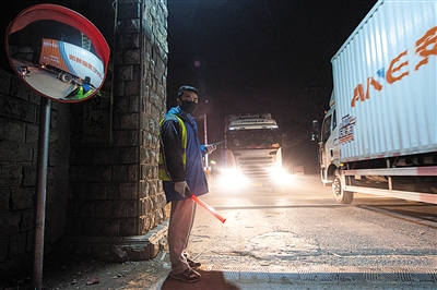 晚上7时许，一名工作人员正在大货车入场必经之路上引导、调度。