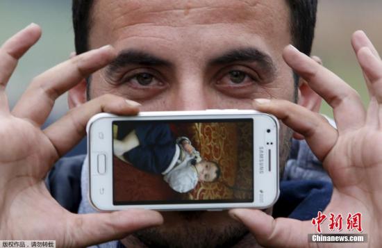 来自多国的众多移民等待通过斯洛文尼亚和奥地利的边境时，用手机照片展示自己的家乡和亲人们的。图为Sirad来自叙利亚Zabadani，他手机中的照片是他儿子Jad。