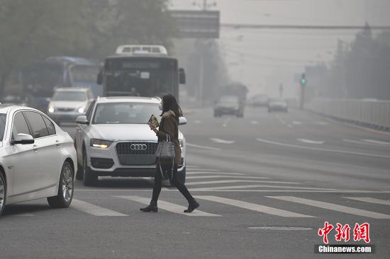 资料图:雾霾天气里一个行人穿过马路。中新网记者 金硕 摄