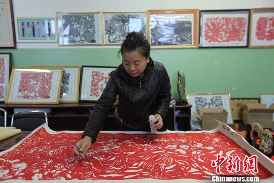 图为巨幅剪纸"复兴之梦"作者康艳在对剪纸作品进行维护. 李江帆
