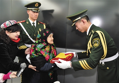 昨日,武警天安门支队官兵向老人赠送国旗。新华社发