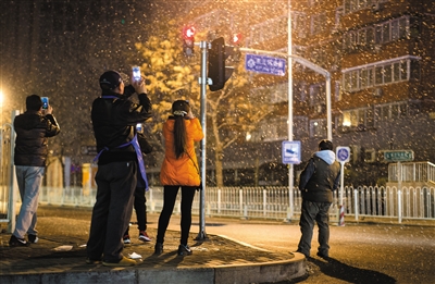 昨日凌晨，劲松桥下，路人驻足拍雪。新京报记者 王子诚 摄